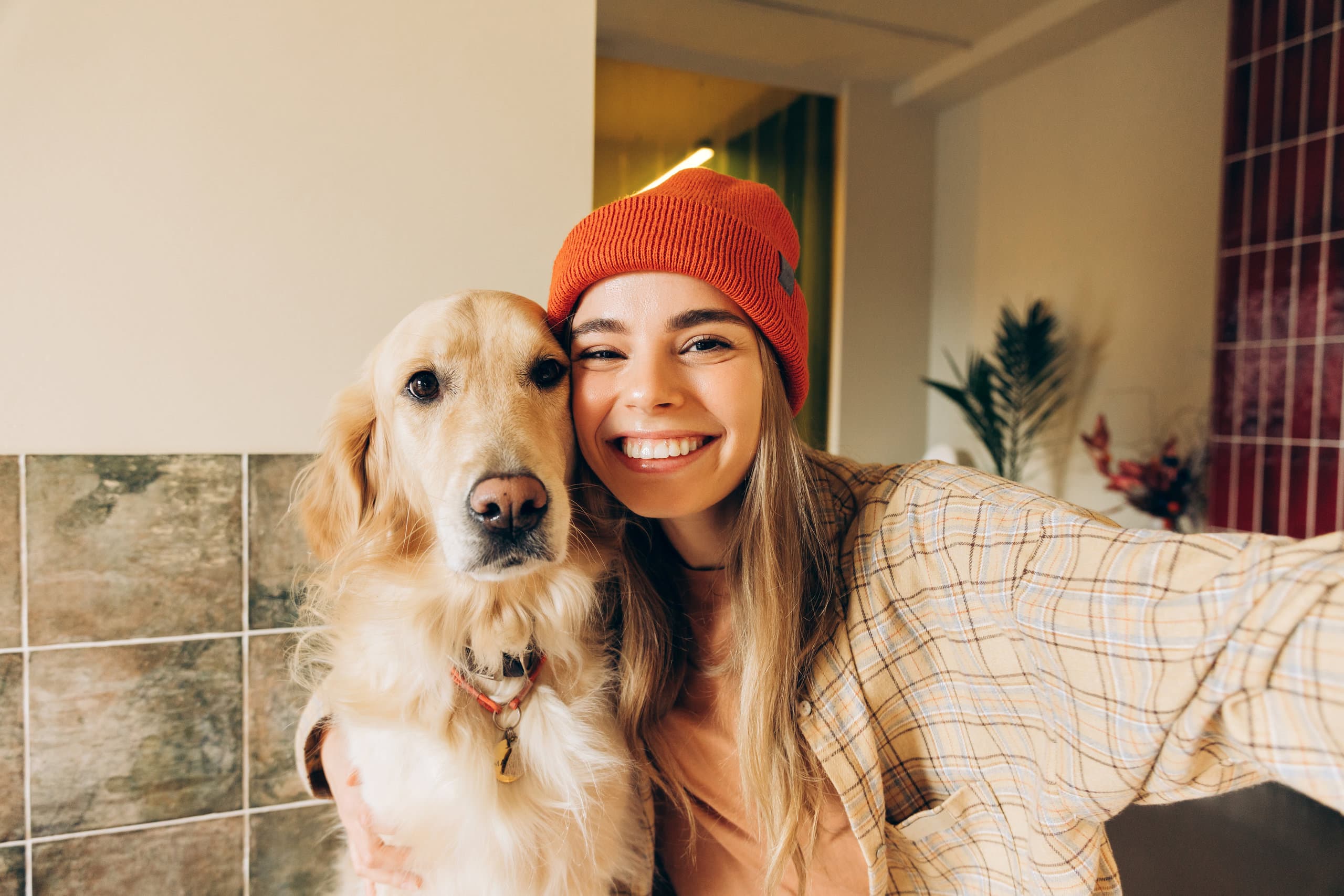 Frau mit oranger Mütze macht ein Selfie mit einem Golden Retriever