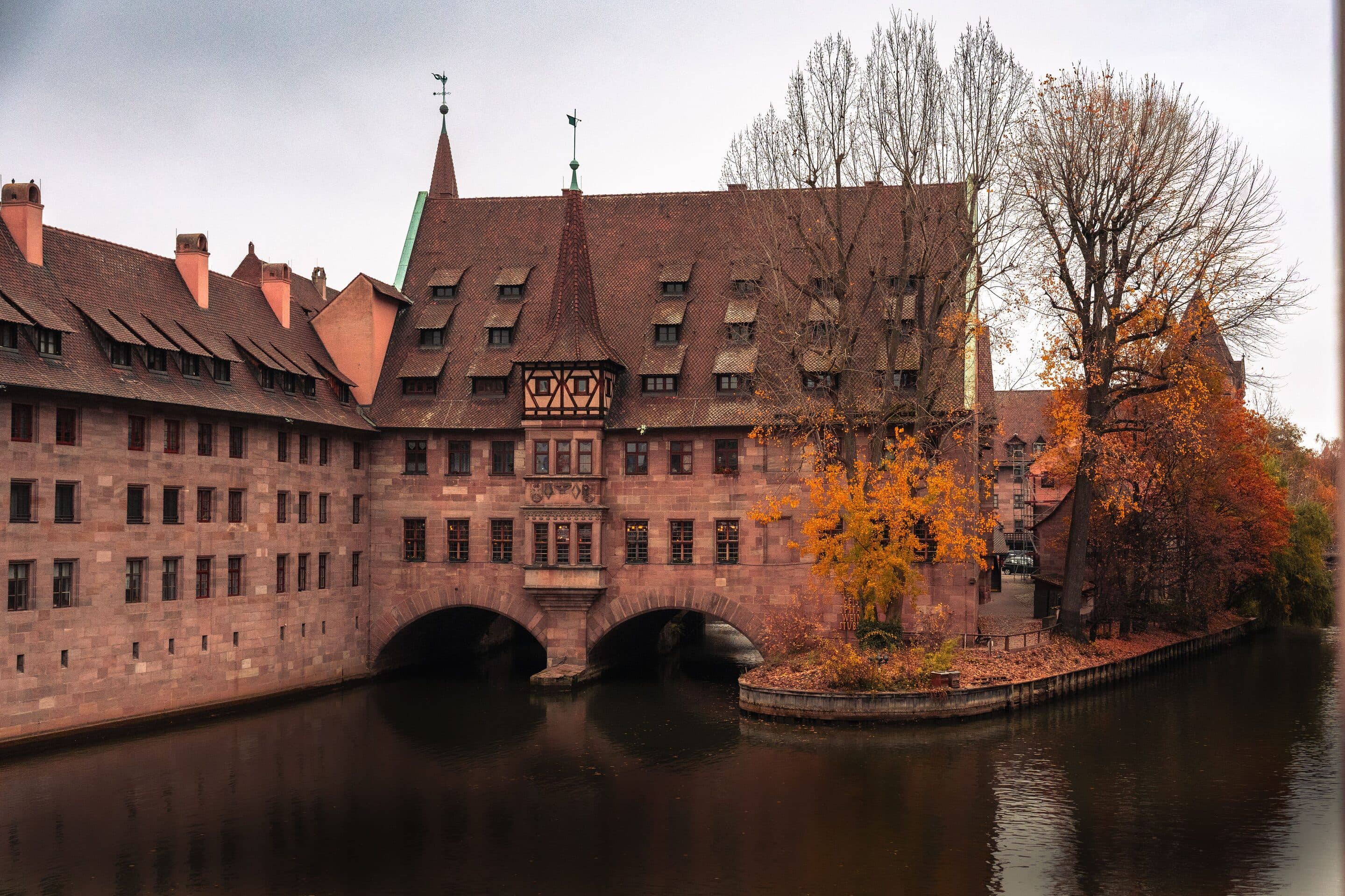 Das Heilig-Geist-Spital in Nürnberg, historisches Gebäude mit Bogenarkaden über der Pegnitz im Herbst