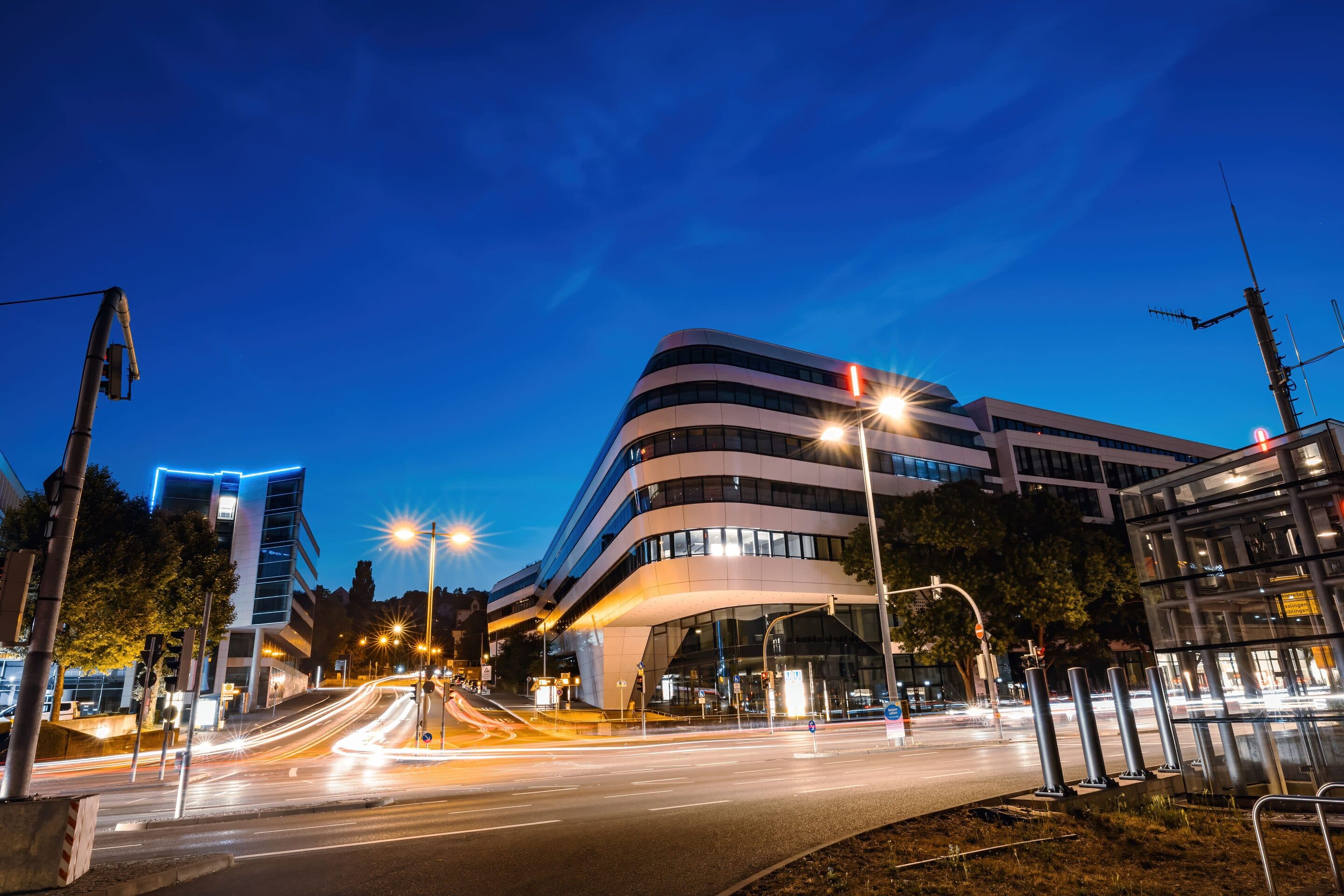 Ein modernes Bürogebäude in Stuttgart zur blauen Stunde, Lichtspuren des Verkehrs auf der Straße davor