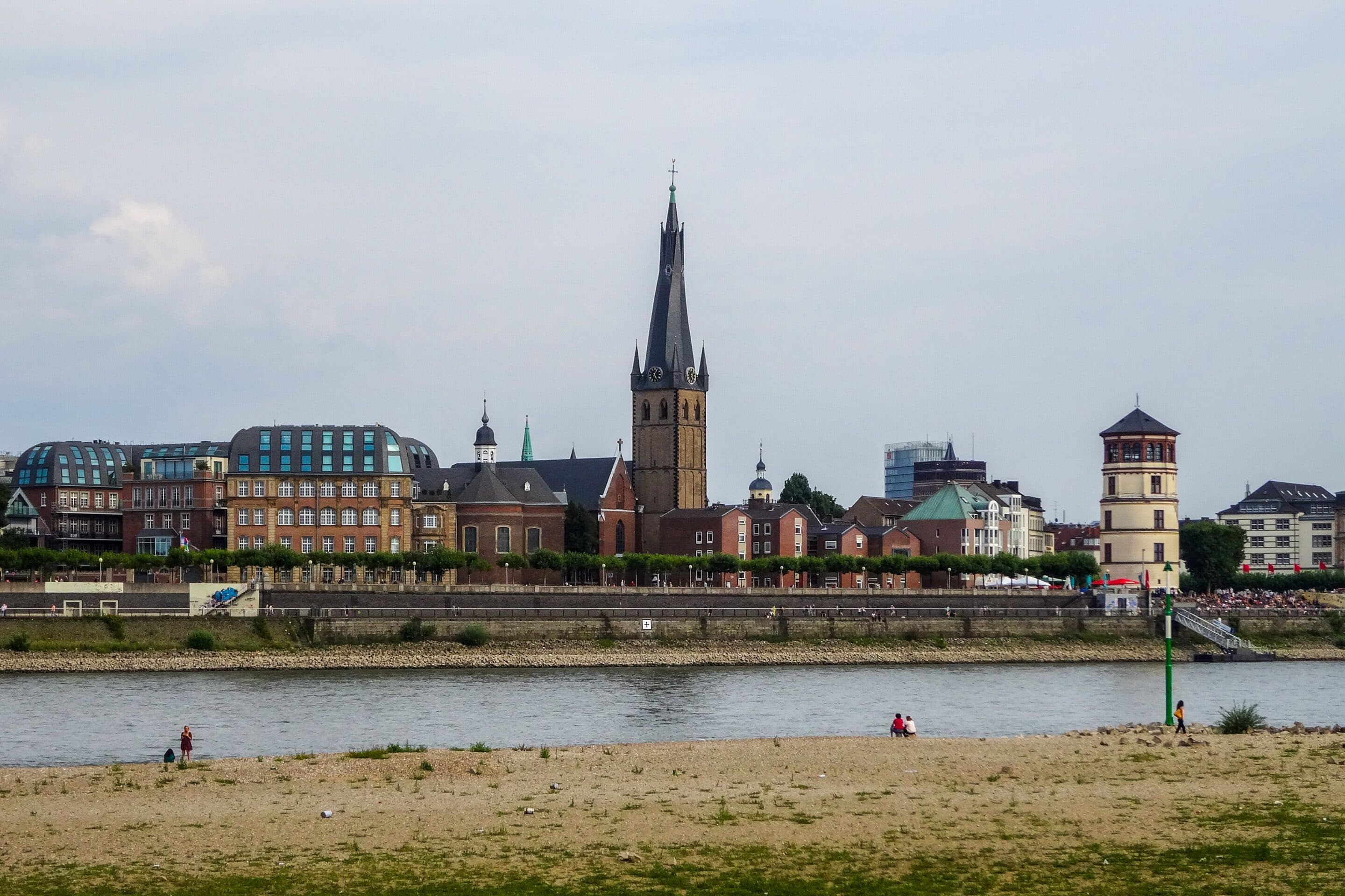 Das Düsseldorfer Rheinufer mit Sandstrand, dahinter die Altstadt mit Lambertuskirche und Schlossturm