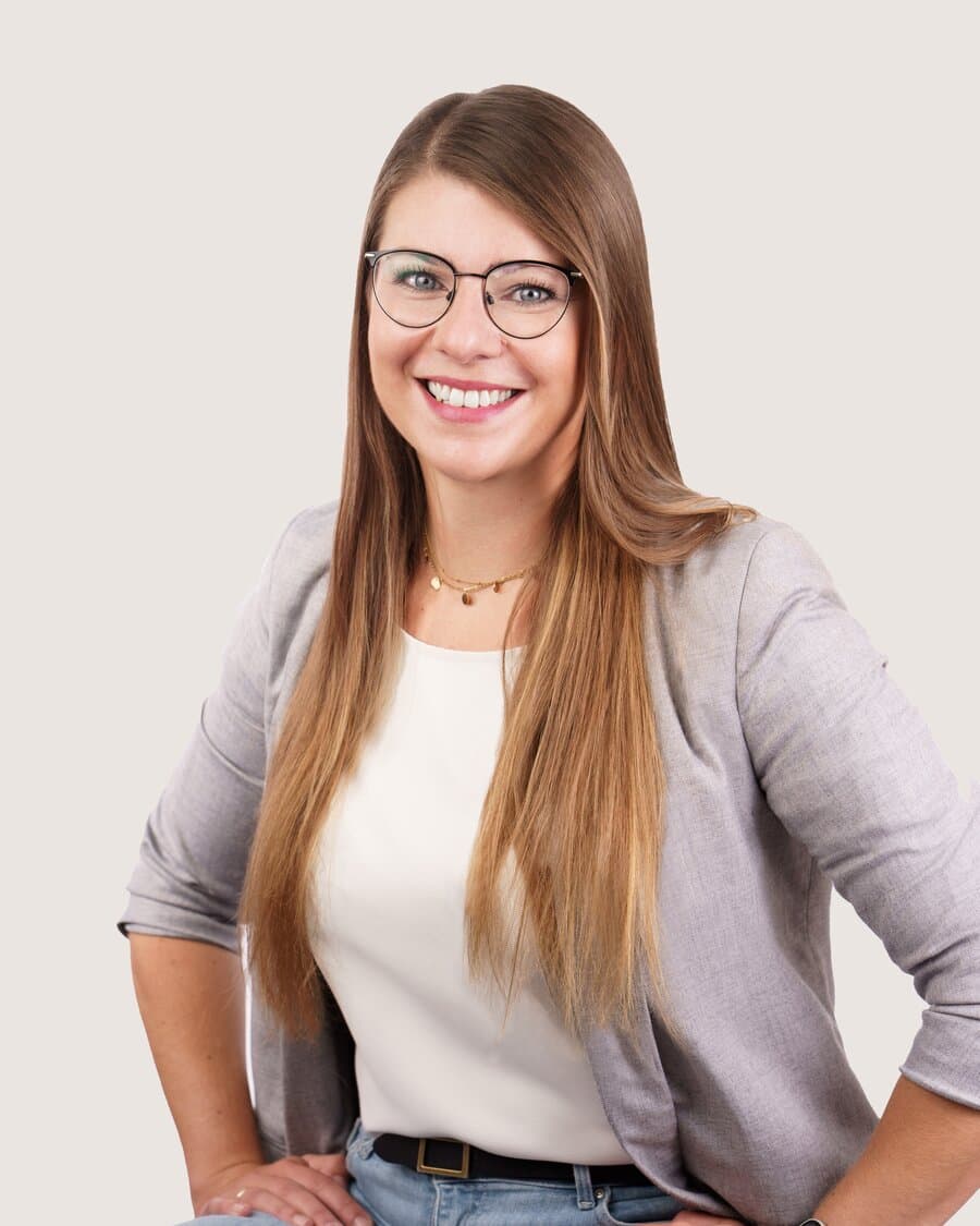 Olga, Standortleiterin in Hamburg, mit Brille und langem braunem Haar, lächelt in die Kamera